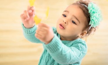 A child in teal holding up yellow paper